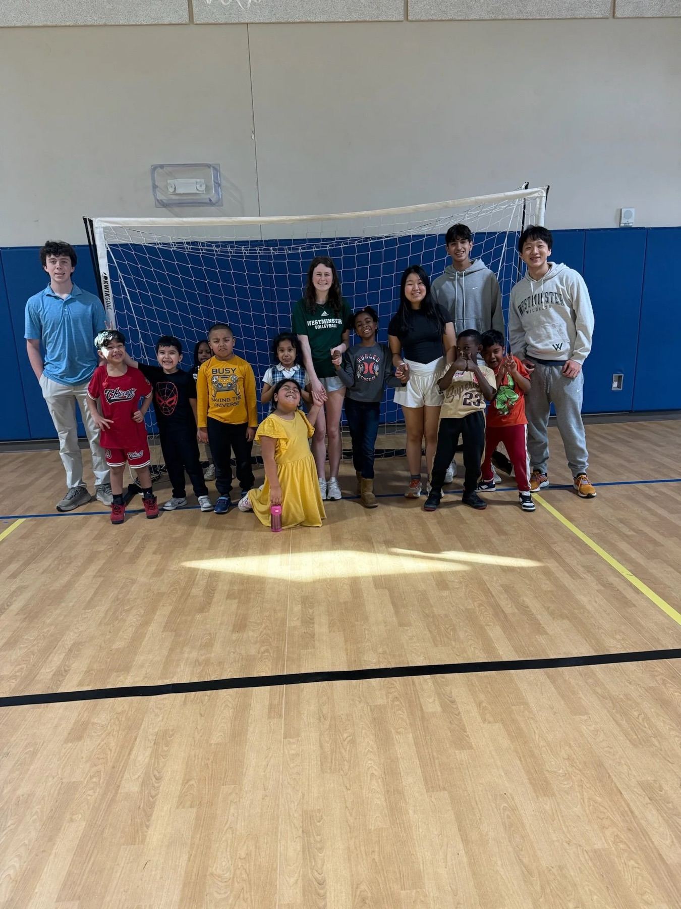 Rise 'N' Reach volunteers standing with a group of children in a community center gymnasium