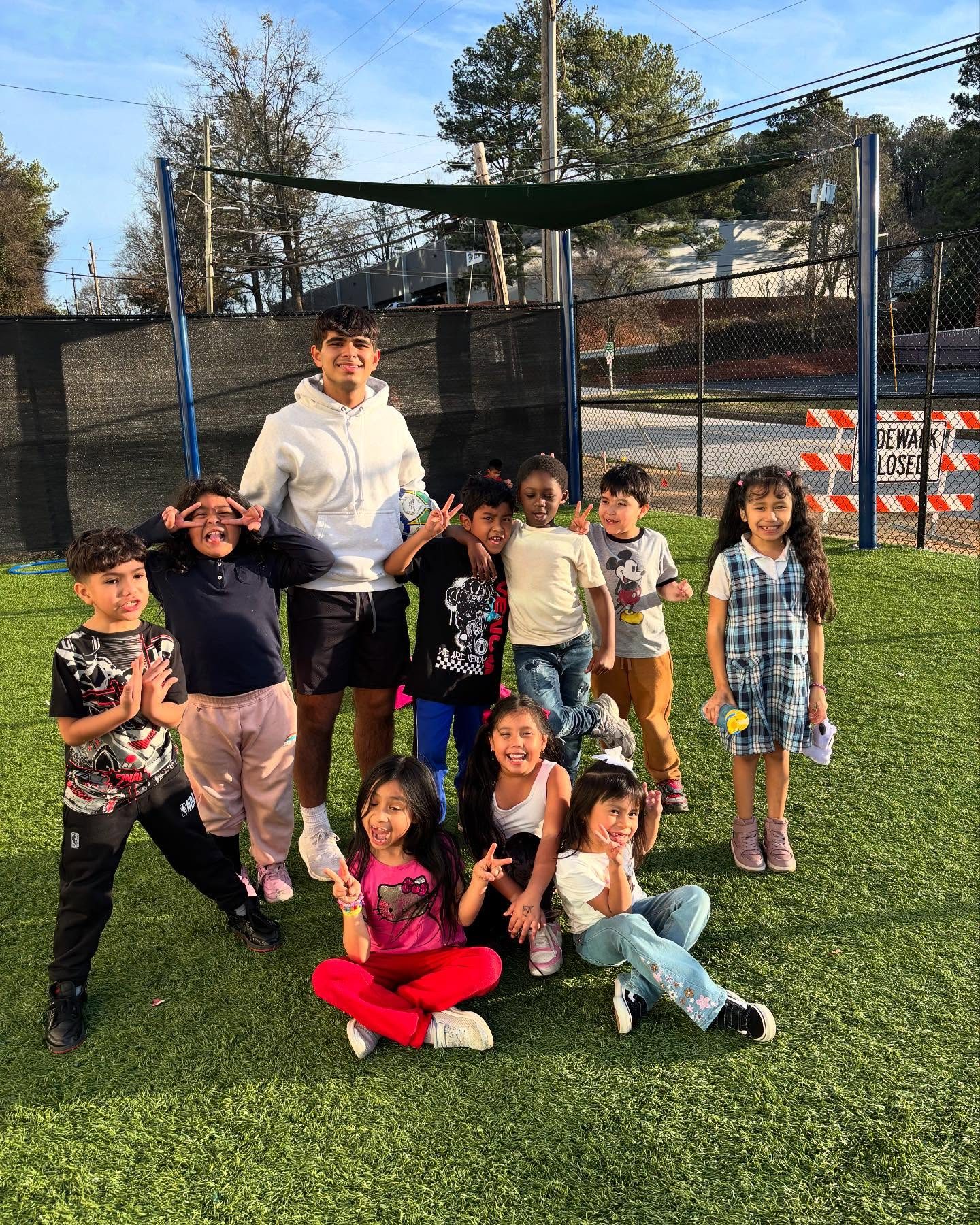 Children and volunteers laughing together on a turf field at Agape Youth & Family Center