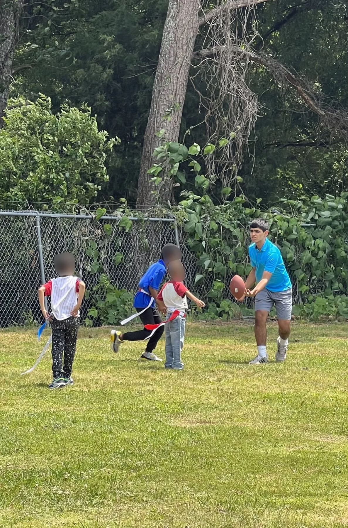A volunteer and a child running together with a football