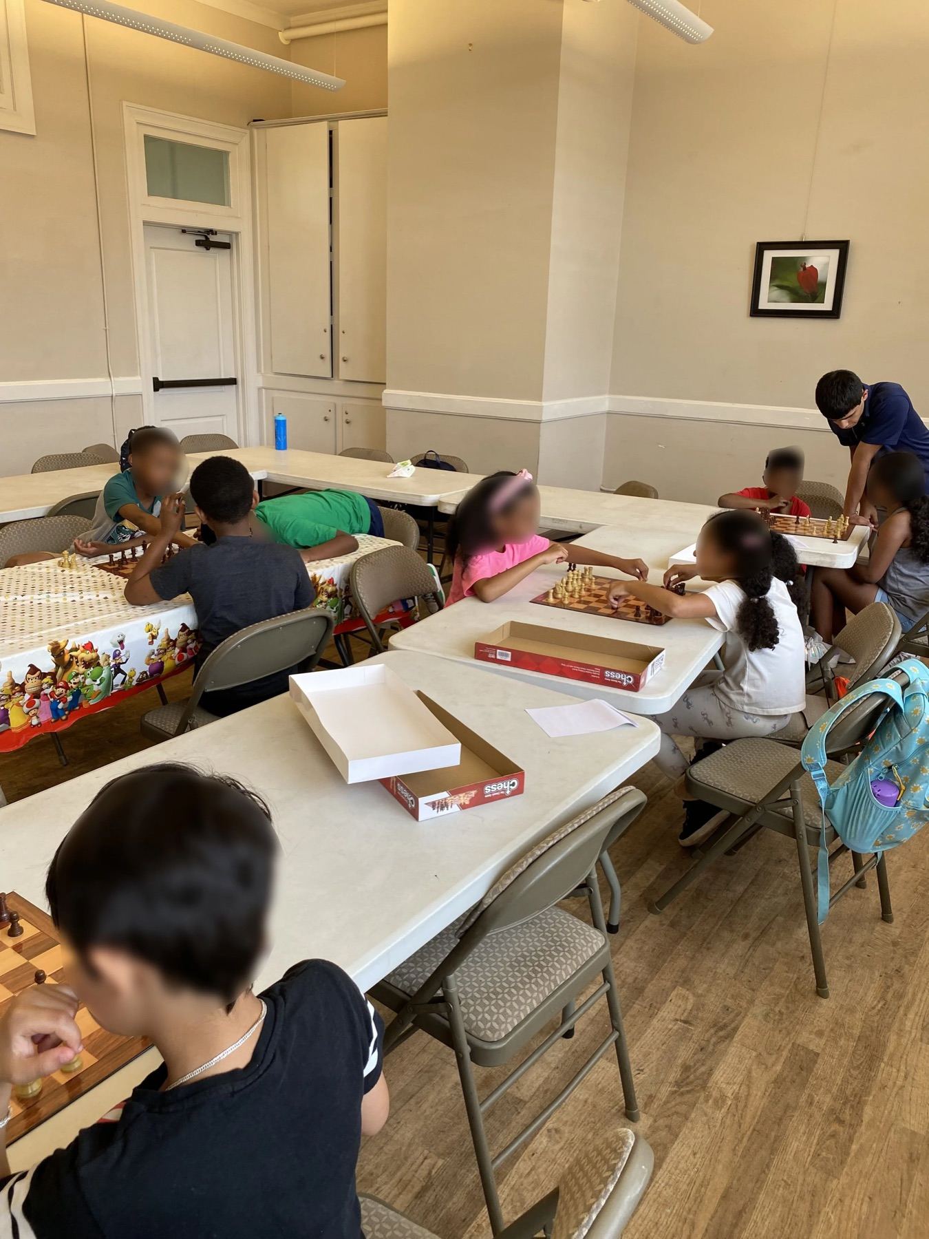 Children and volunteers gathered around a long table covered in games and activity supplies
