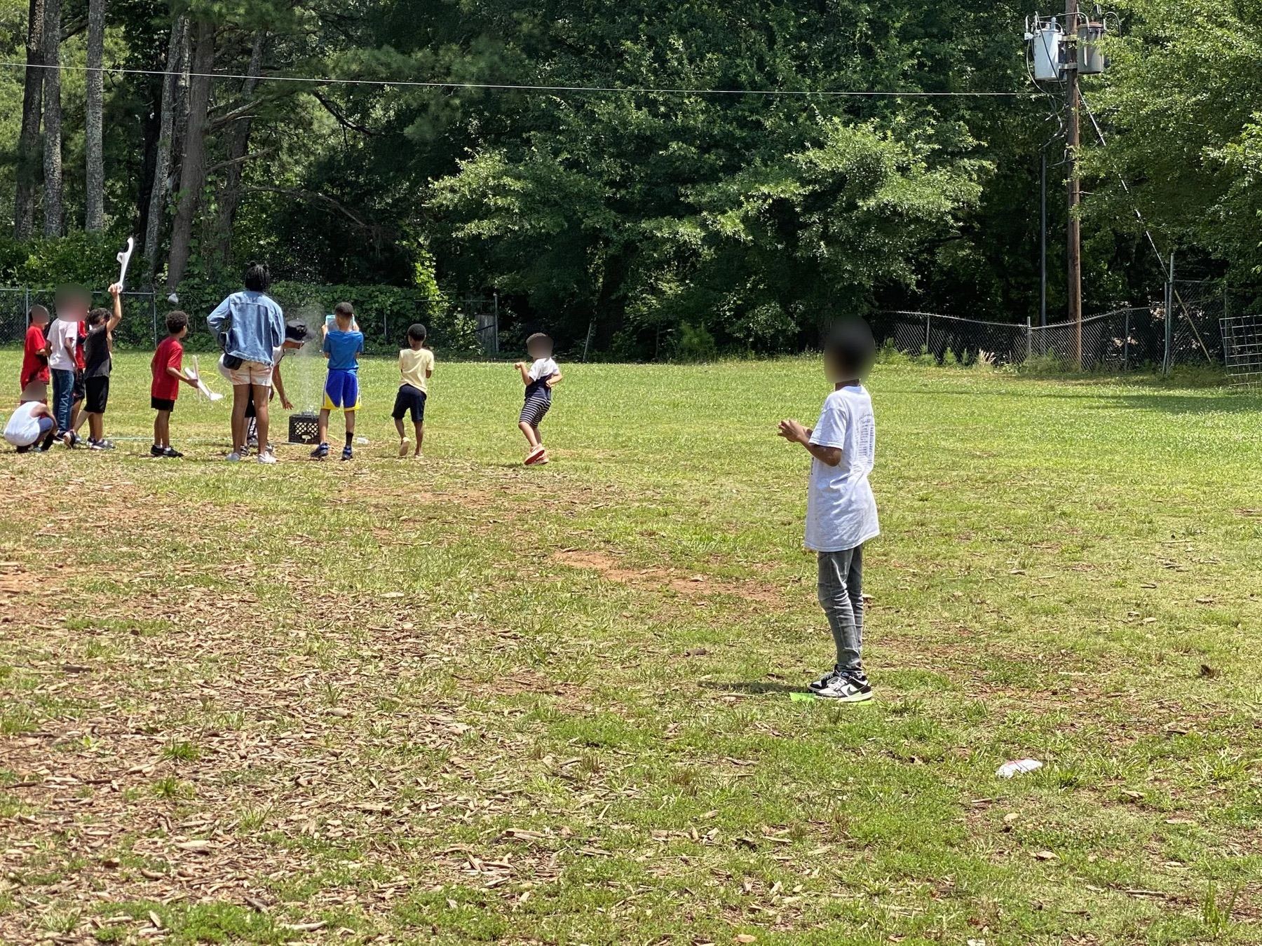 Children running a passing drill across a grass field marked with cones