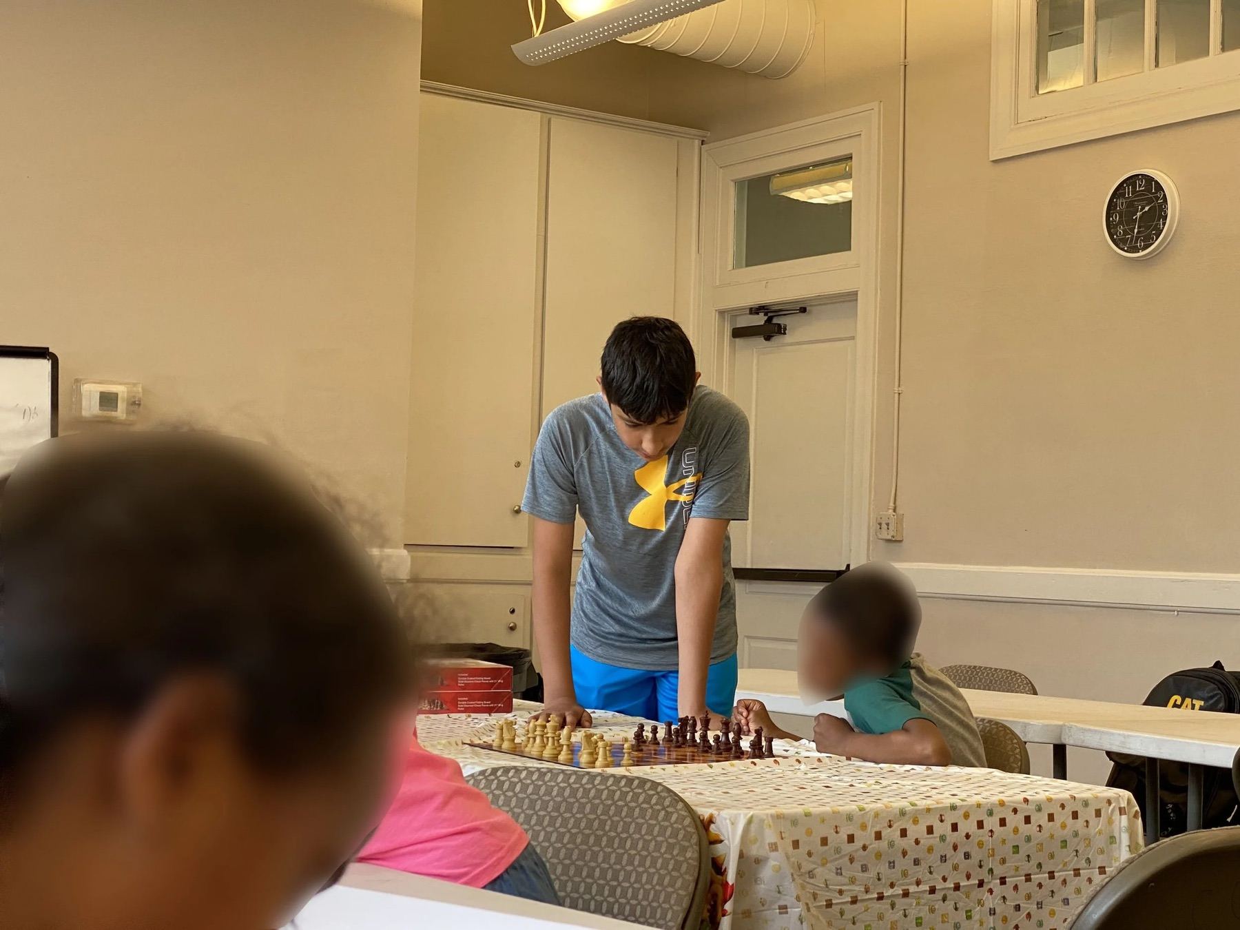 A volunteer playing chess with a child at a table inside a community center
