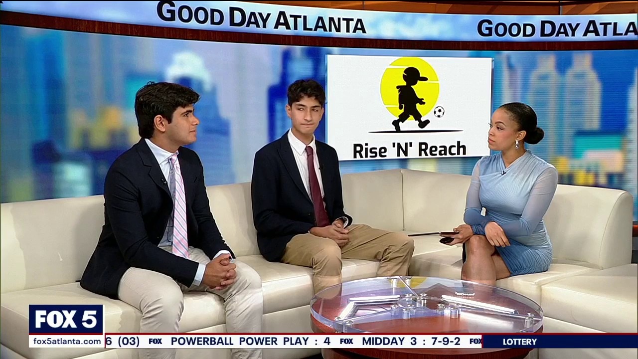 Still from FOX 5 Good Day Atlanta: co-founders Rohan and Rishab Anand seated on the studio couch beside the host, with the Rise 'N' Reach logo on screen